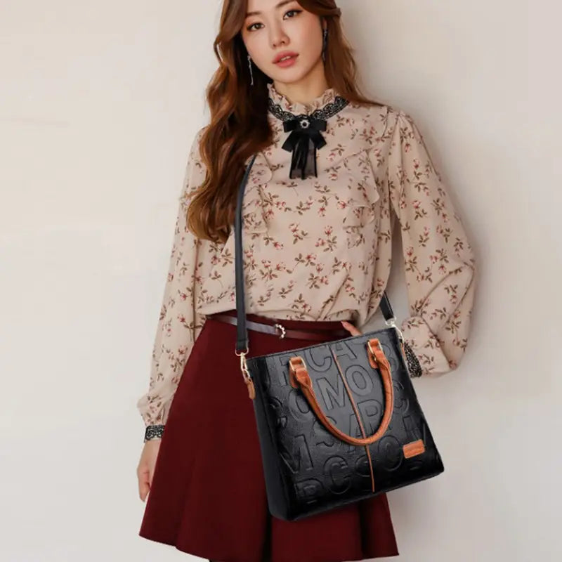 Black crossbody handbag in pu leather with a black body, tan leather handles, and a monogram pattern representing style1 style2 style1.