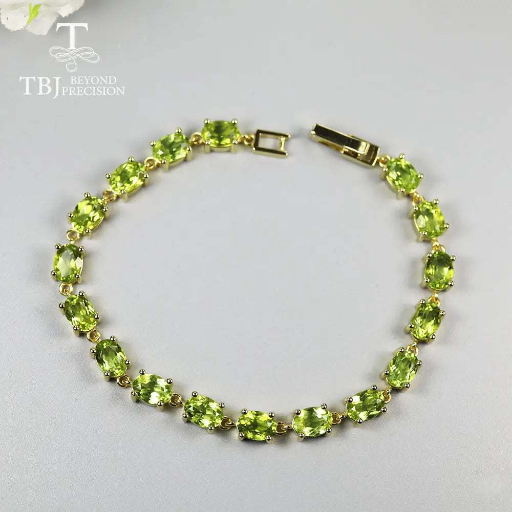 Una pulsera tipo tenis delicada de plata de ley con peridoto, con piedras de peridoto verde ovaladas dispuestas de manera uniforme, en un diseño clásico de eslabón en tono dorado.