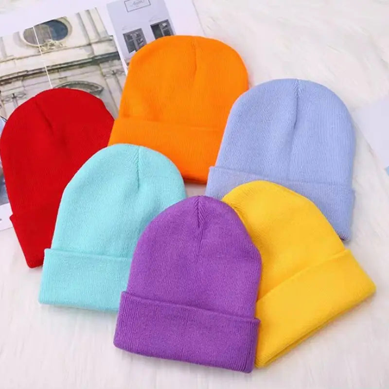 Une collection de bonnets en tricot à revers colorés aux teintes vives, rouge, orange, bleu clair, violet et jaune, conçus comme des bonnets d’hiver décontractés unisexe unis, avec un excellent service client et des options d’expédition via China Post.