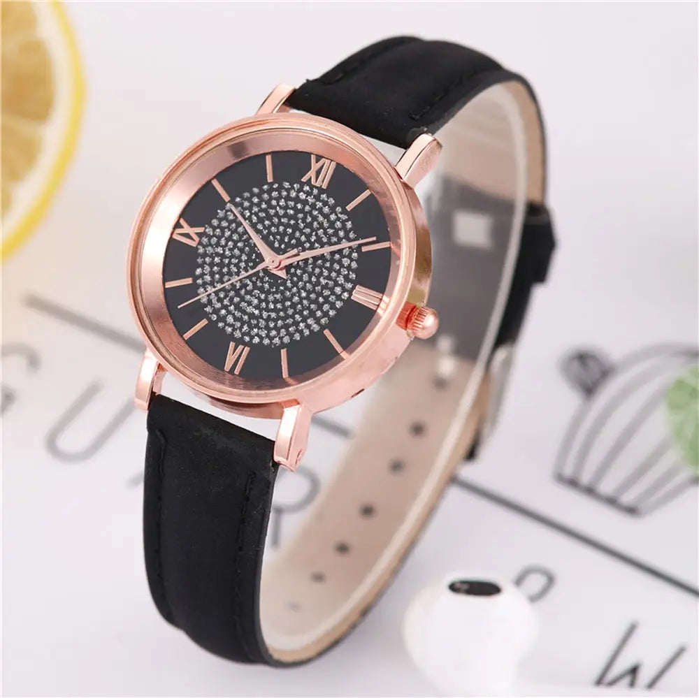 Rose gold crystal quartz women watch featuring a black dial with sparkling rhinestones and roman numerals paired with a sleek black leather strap.