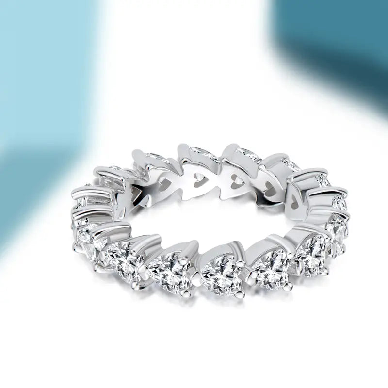 Une bague d’éternité cœur en argent sterling étincelante, dotée d’une rangée continue de diamants taillés en forme de cœur et en coupes rondes.