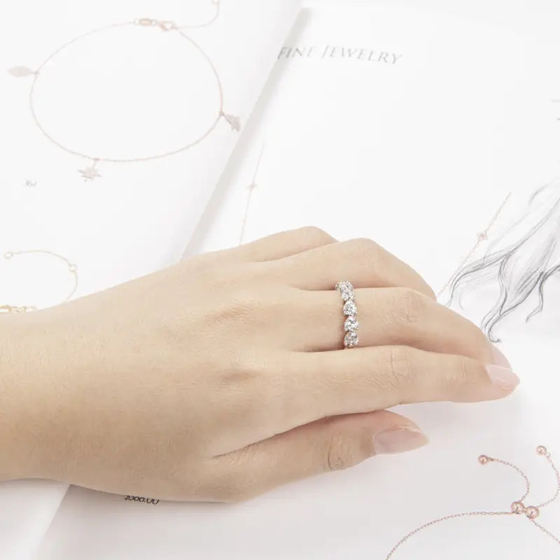 Une bague d’éternité cœur en argent sterling, dotée d’une monture délicate, avec une rangée de cinq diamants ronds étincelants, dans un design continu et élégant.
