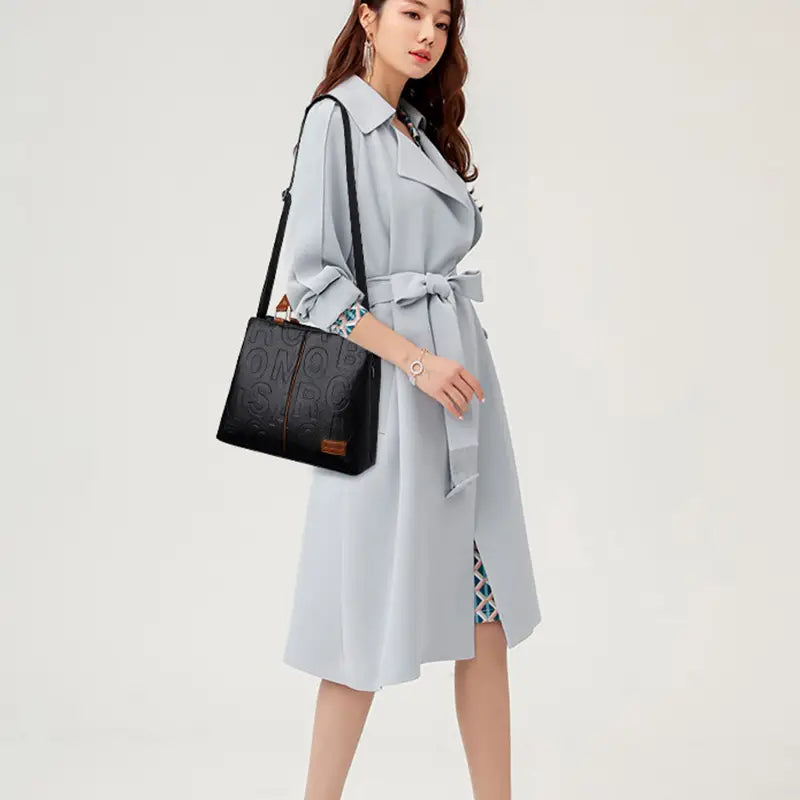 Black crossbody handbag in pu leather with black textured material, embossed logo, and brown leather accent in style1 style2 design.