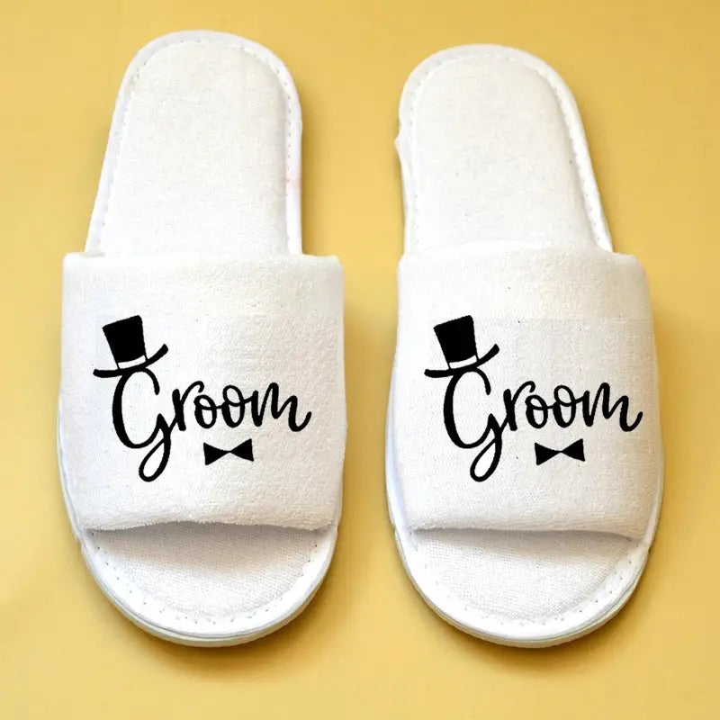 Weiße flauschige Schlupf-Slipper mit schwarzem „Bräutigam“-Text sowie Zylinderhut- und Fliege-Design für Brautparty-Slipper und Hochzeits-Slipper.