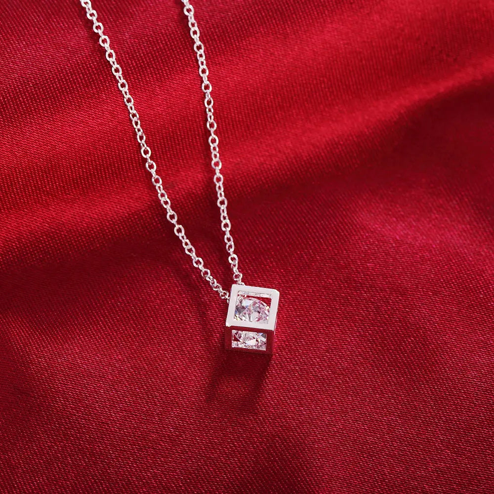 Collier délicat en chaîne d’argent, avec un pendentif carré, orné de deux pierres en zirconium transparentes à facettes disposées au centre.