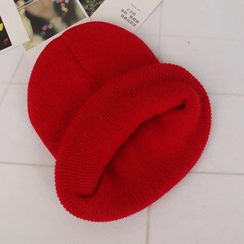 Un bonnet en tricot rouge vif avec une texture côtelée et un revers replié, adapté aux tenues d’hiver décontractées unisexe, expédié via China Post avec un service client fiable.