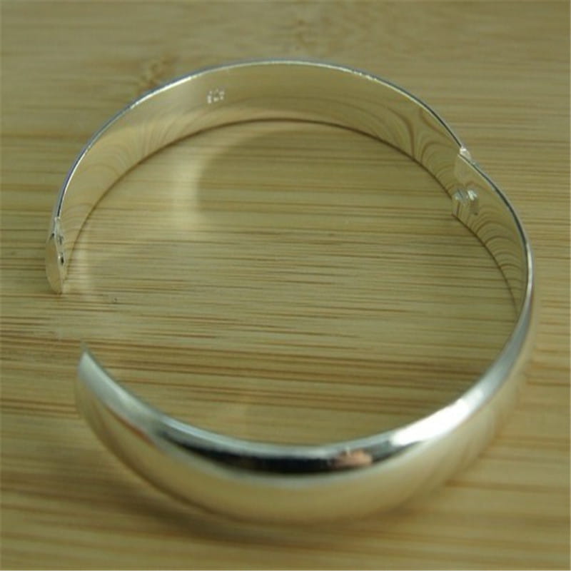 Una pulsera de plata pulida elegante, 925, brazalete abierto para mujer, que presenta un diseño liso y redondeado y un patrón sutil de grabado en el borde interior, ideal como brazaletes pulseras mujer.