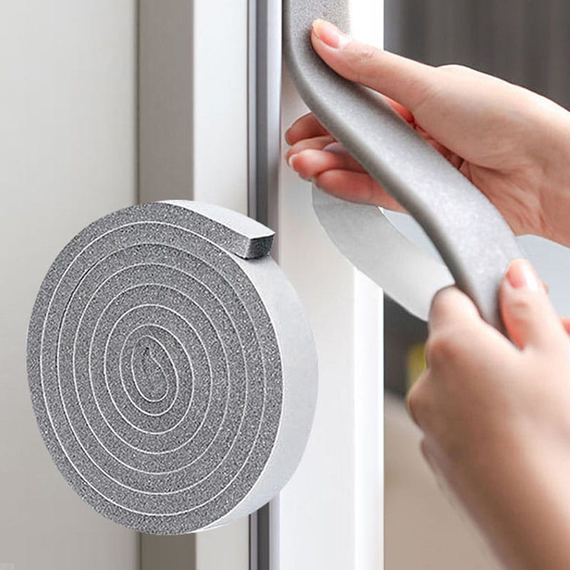 Bande d’étanchéité en mousse grise pour calfeutrage, pour portes et fenêtres, avec une surface texturée et un support adhésif.