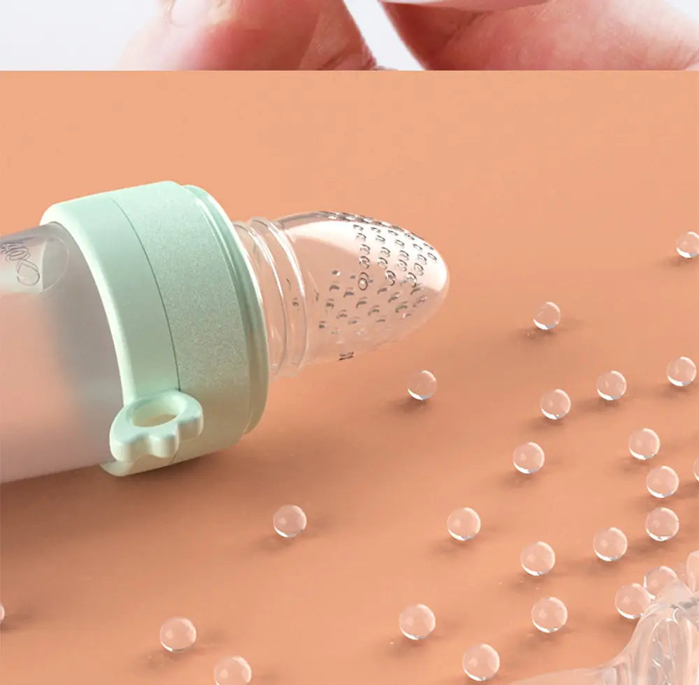 Eine durchscheinende Silikon-Babysqueeze-Feedingflasche und ein Löffelspender mit mintgrüner Silikonkappe und punktierter Spitze, ausgelegt für einfaches Füttern.