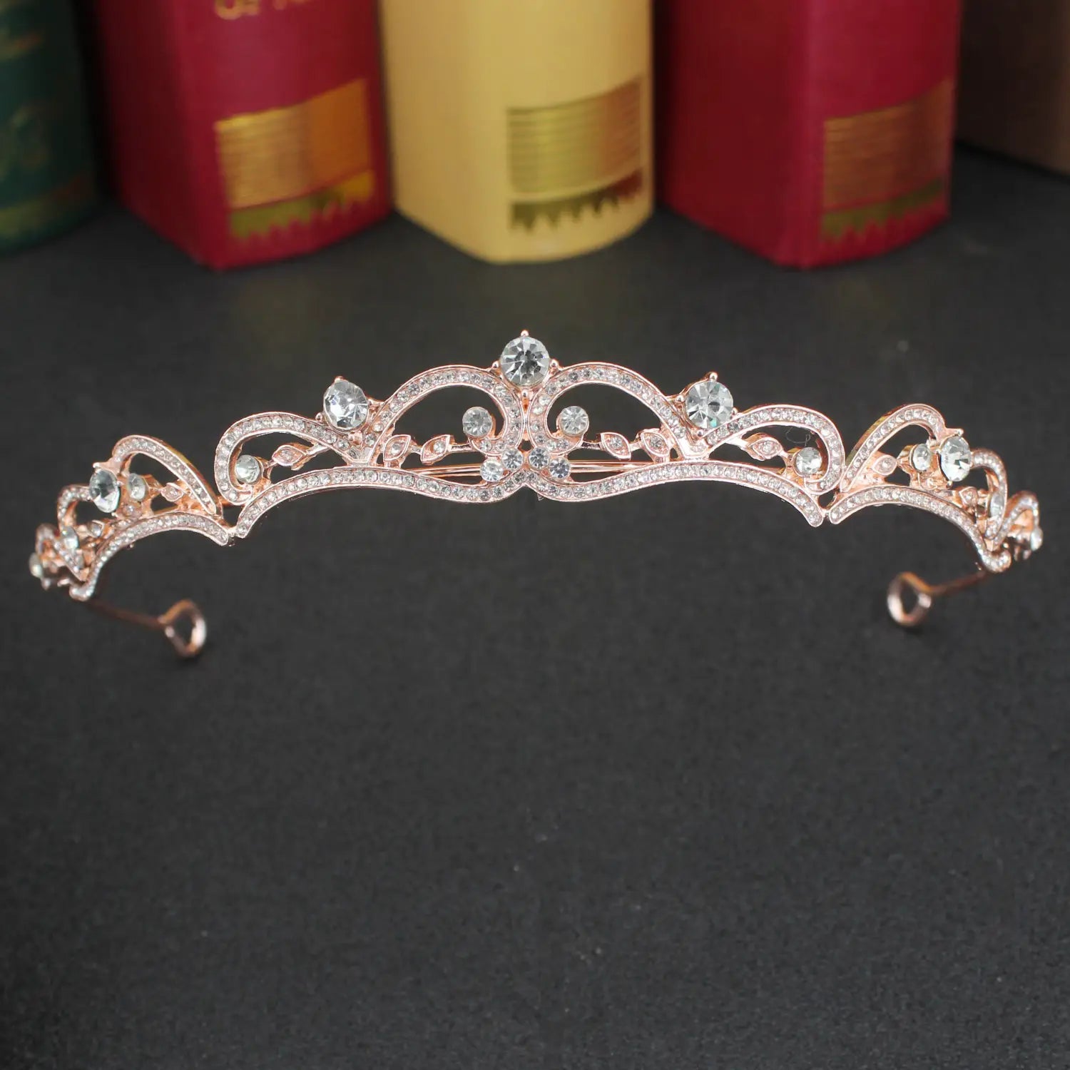 Una tiara de novia de cristal rosa dorado delicada con cristales transparentes brillantes y un detallado floral intrincado para bodas.