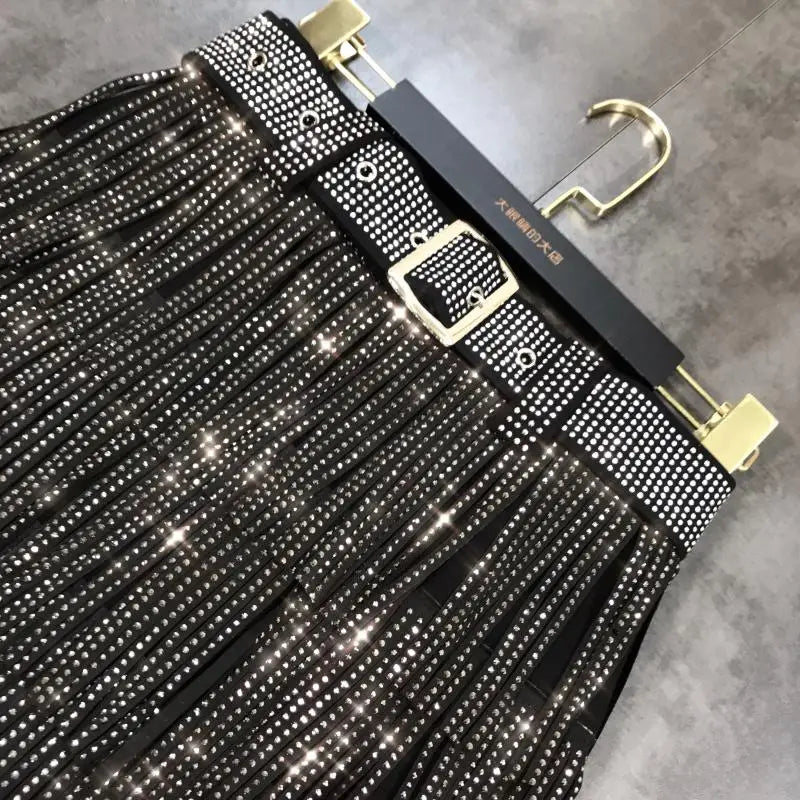 Mini-jupe noire à franges taille haute, agrémentée de strass scintillants et d’une boucle à tonalité dorée.
