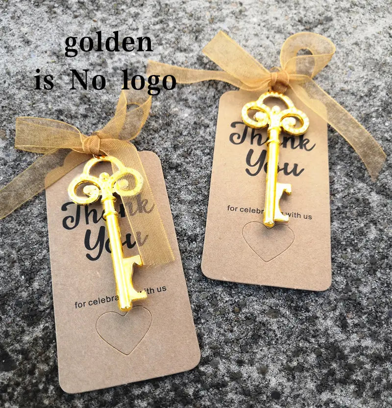 Encantos de abridor de botellas con llave ornamentados color dorado, con trabajos de filigrana intrincados, sujetos a etiquetas de papel marrón atadas con cinta dorada semitransparente para recuerdos de boda personalizados