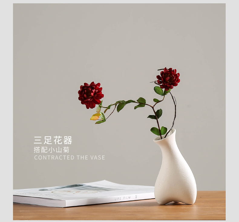 Modern white ceramic vase with a sleek curved body and three small feet designed for floral decor.
