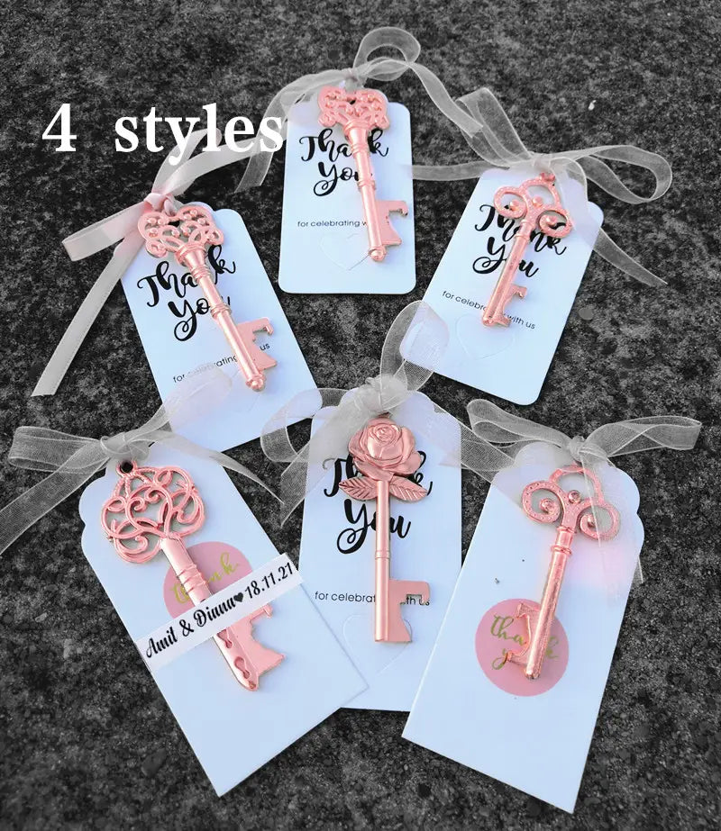 Recuerdos abridores de botellas para bodas personalizados con forma de llave en acabado metálico oro rosa, con diseños intrincados y lazos de cinta semitransparente adheridos.