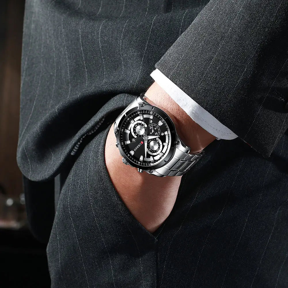 Silberfarbene Edelstahl-Chronographenuhr von Curren mit schwarzem Zifferblatt und mehreren Hilfszifferblättern, getragen am Handgelenk eines Mannes.