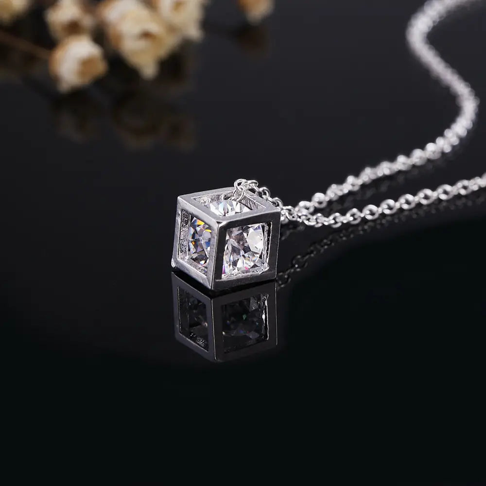 Collier de pendentif en zirconium carré argenté, avec un cube en argent comportant des cristaux transparents à facettes, montés dans un cadre métallique épuré.