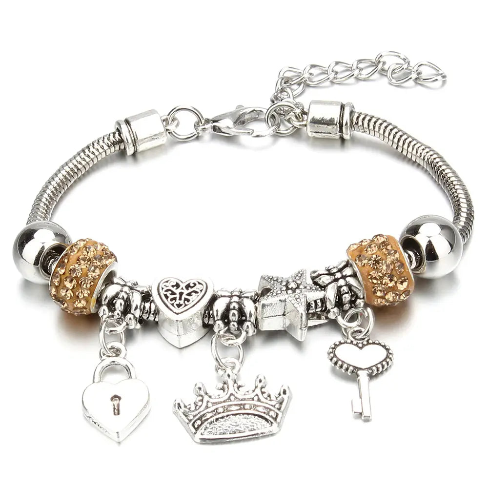 Charm bracelet for women featuring a silver snake chain adorned with sparkling gold and silver crown, heart key, lock, and gift box charms.