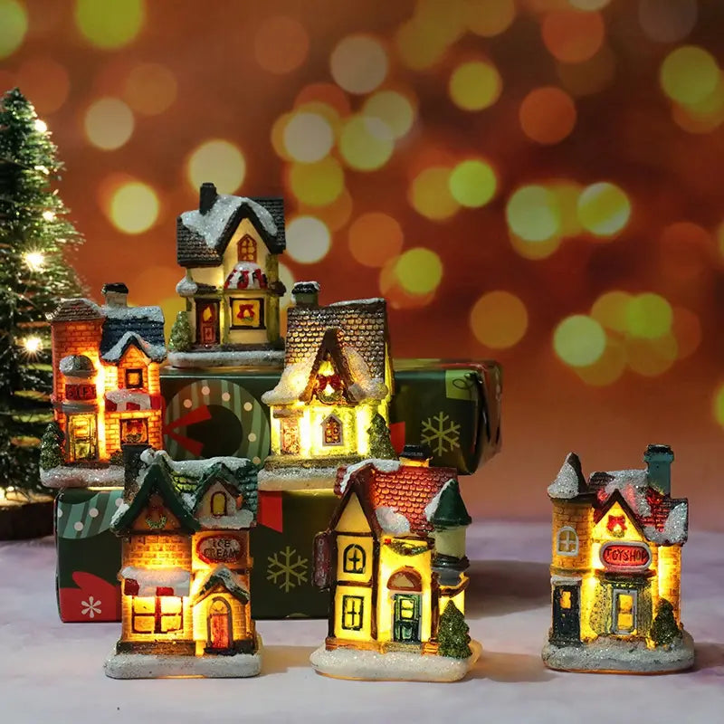 Un ensemble de maisons de village de Noël à LED alimentées par piles, avec des toits blanchis par la neige et des fenêtres lumineuses, réalisées en céramique peinte et en résine, pour un éclairage nocturne festif.