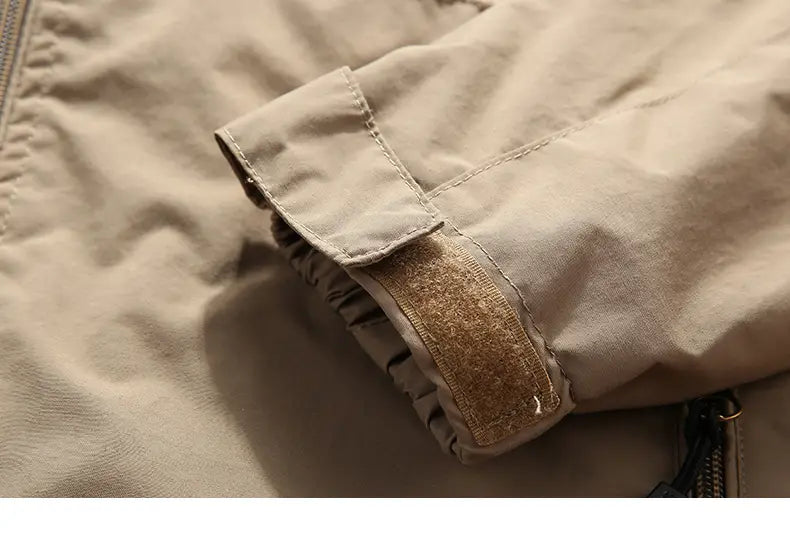 ベージュのメンズ防水ハイキングジャケット袖。タンカラーのベルクロパッチと補強ステッチを備え、フード付きウィンドブレーカーとして設計されています。