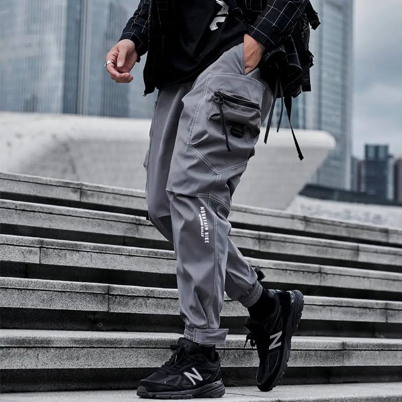 Herren schwarze taktische Cargo-Jogginghosen in Grau mit mehreren Taschen und einem dezenten weißen Logo am Bein, entworfen für Streetwear.