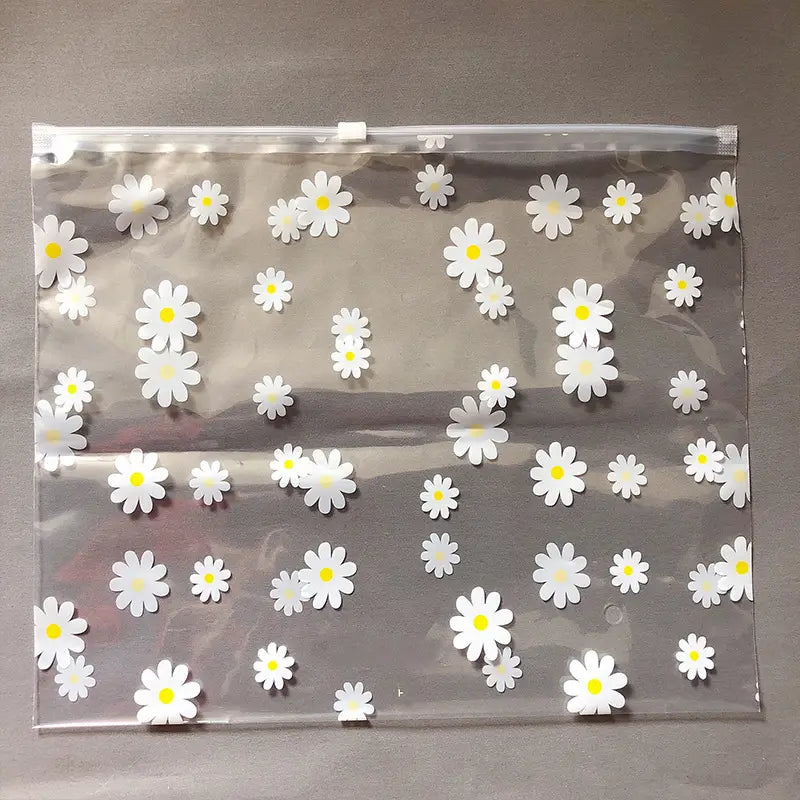 Blumige, durchsichtige Reisekosmetiktasche aus durchsichtigem Kunststoff mit einem Reißverschlussverschluss, verziert mit weißen Gänseblümchen mit gelben Zentren.