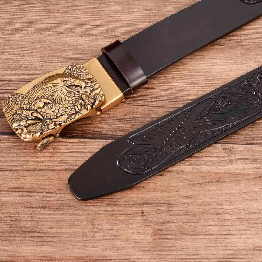 Ceinture à cliquet en cuir pour homme avec une boucle d’aigle tête dorée, présentant des détails fins sur une lanière en cuir brun foncé.