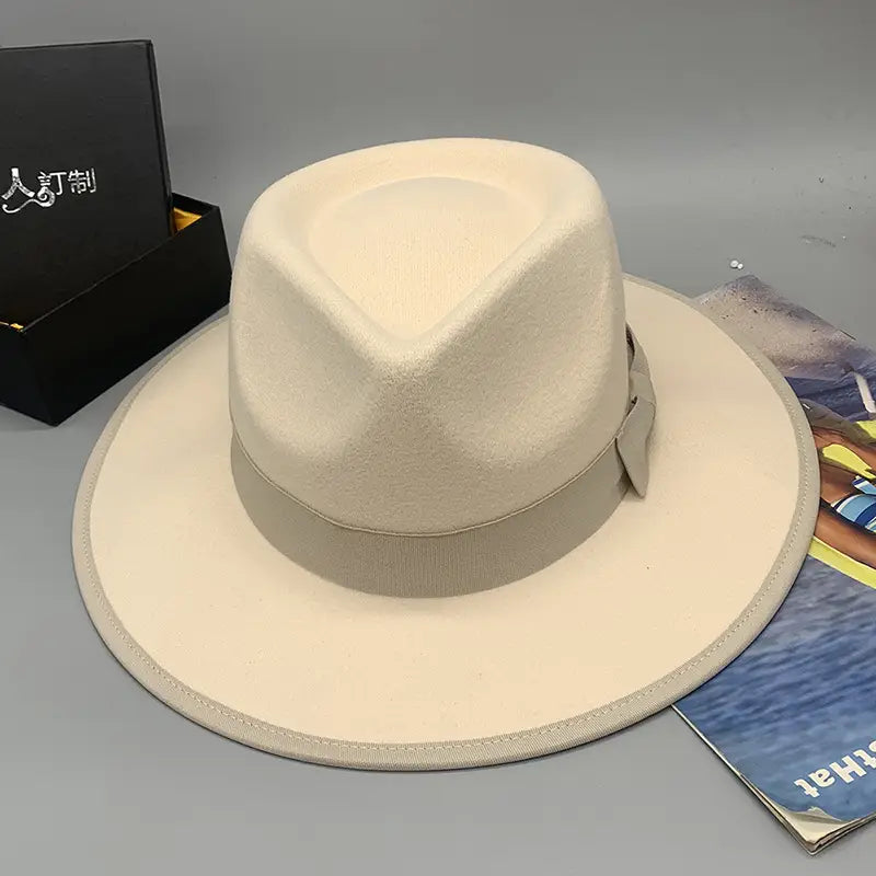Cream-colored unisex woolen felt fedora hat with a matching ribbon band and subtle stitching details featuring a feather accent.