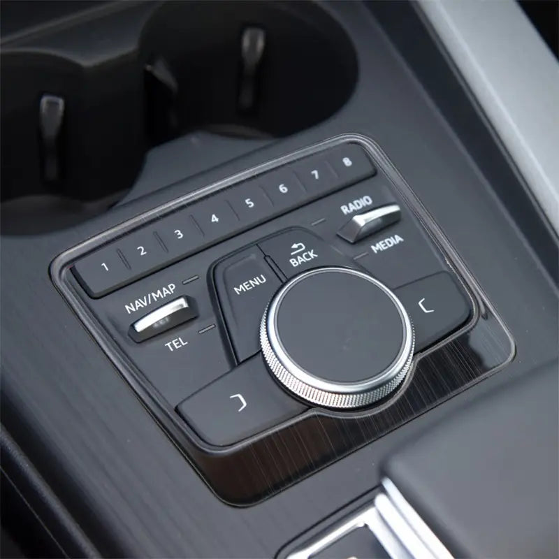 Audi A4 B9 A5 Schalthebel-Wandhalterung mit Becherhalter-Einfassung in Schwarz und Silber, mit einem Bedienteil für die Car-Audio-Funktion, zentralem Drehregler und beschrifteten Tasten für „Nav/Karten“, „TEL“, „Menü“, „Zurück“, „Radio“ und „Media“.