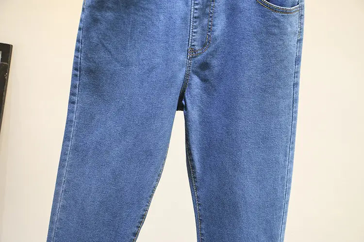 Jeans en denim bleu clair extensible taille haute à coupe classique de jambe droite et détails de surpiqûres visibles.