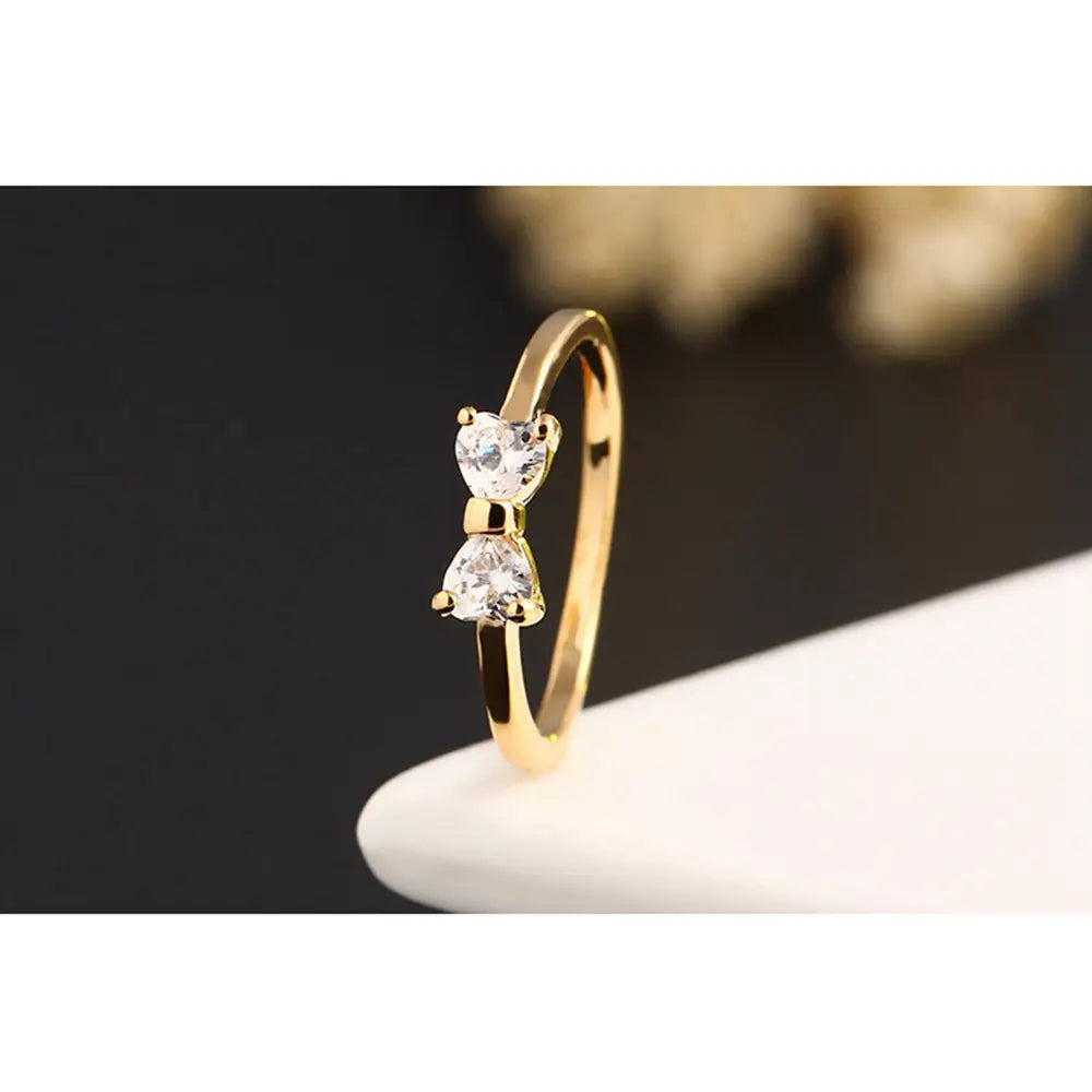 Bague de mariage en nœud en argent sterling en oxyde de zirconium cubique, de ton or, présentant deux cristaux clairs en forme de cœur dans un design de nœud.