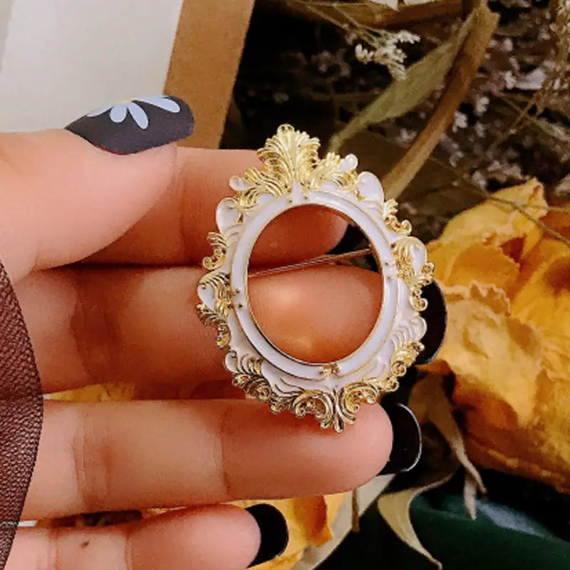 Broche para marco de cuadro con arte de David barroco ovalado y ornamentado, con marco de esmalte blanco, detalles de filigrana en oro y un centro de color ámbar.