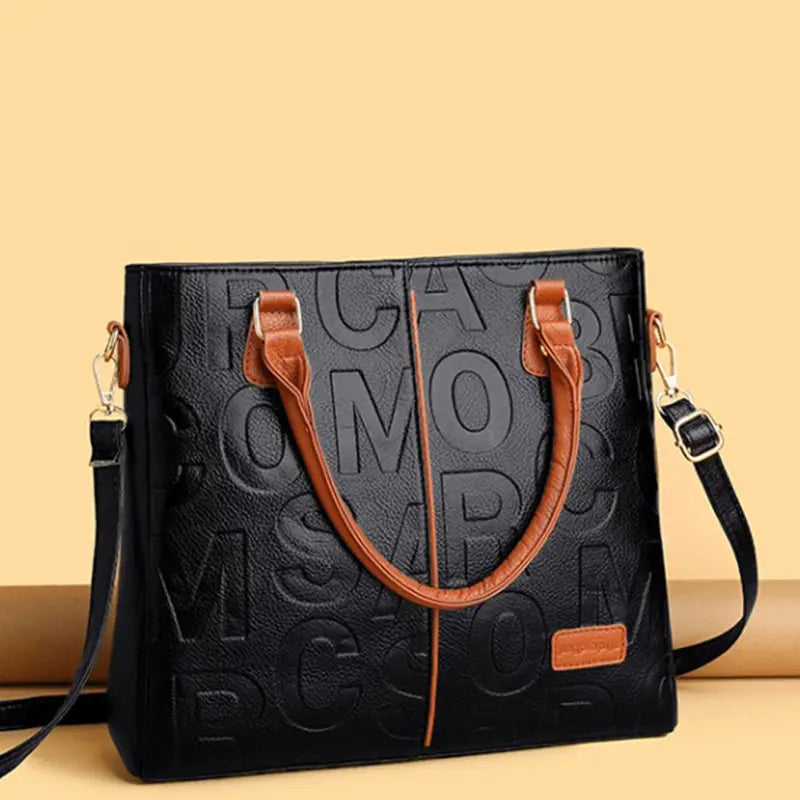 black crossbody handbag style1 style2 made of black faux leather tote bag with embossed lettering and tan handles and shoulder strap in satchel style