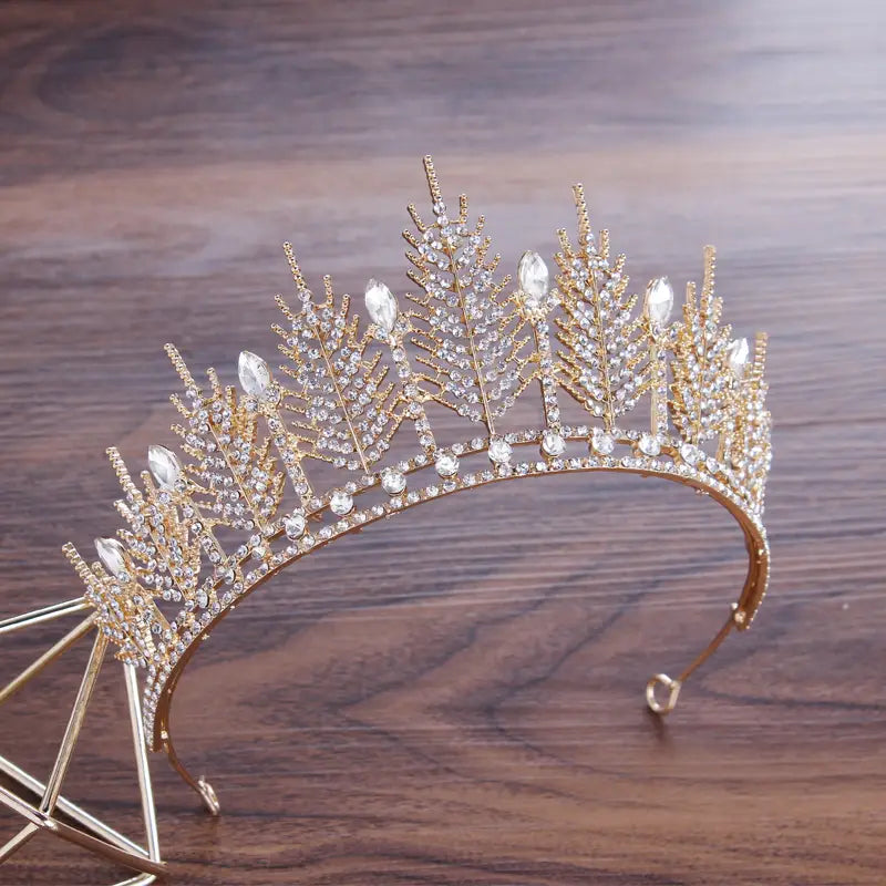 Gold-colored crystal bridal tiara with intricate leaf designs and sparkling clear crystals for wedding crown headpiece.