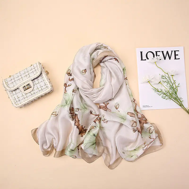 Étole foulard en soie « Van Gogh Almond Blossom » dans une soie aux tons clairs, avec un imprimé botanique subtil comprenant des feuilles vertes et des glands bruns.