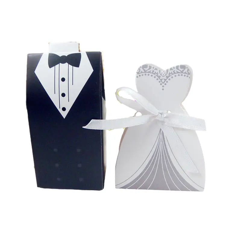 Elegant black and white bride and groom wedding favor candy boxes shaped like a tuxedo and a lace-trimmed gown tied with satin ribbon in a set of 30 pieces.