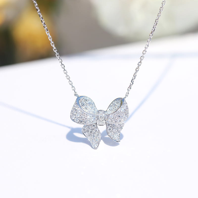 A sparkling silver bow-shaped pendant necklace adorned with numerous clear faceted zircon stones from the silver bowknot zircon necklace and earrings set.