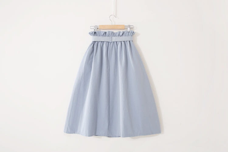 Une jupe midi en coton bleu clair, douce, à silhouette en ligne A, avec une taille haute et une ceinture élastiquée à volants, adaptée à une tenue décontractée.