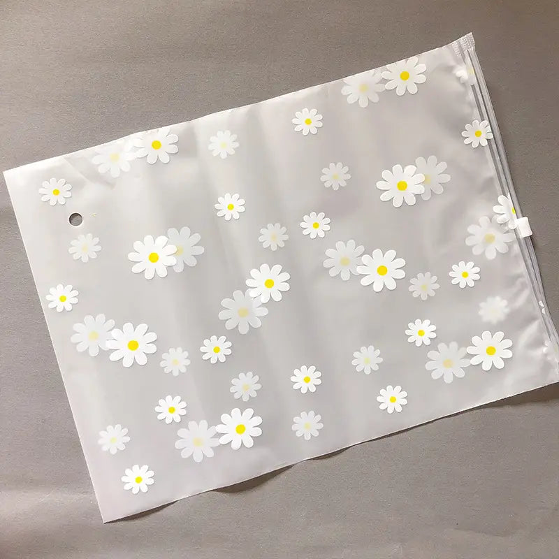 Blumige, durchsichtige Reisekosmetiktasche aus transparentem weißem Kunststoff mit einem Muster aus gedruckten Gänseblümchen mit gelben Zentren.