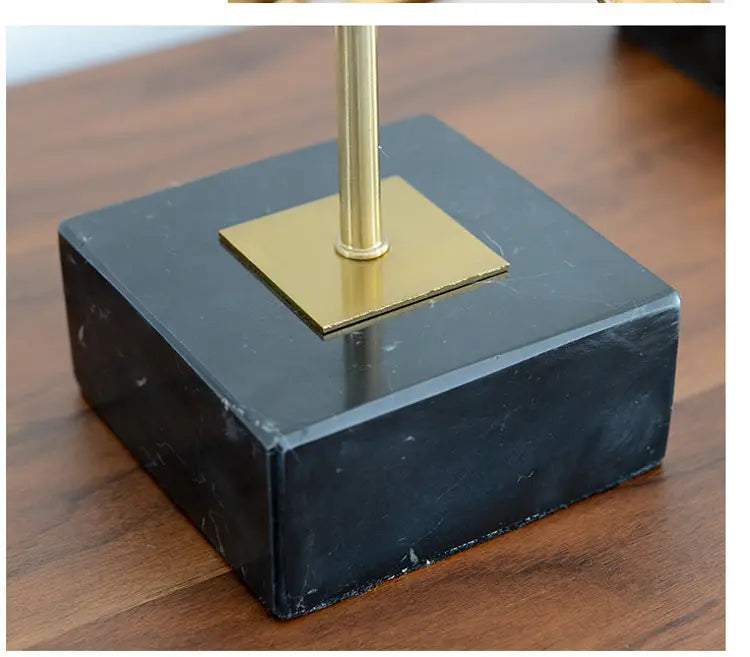 black marble base with gold toned square plate and central brass stem in gold metal abstract sculpture office desk decor.