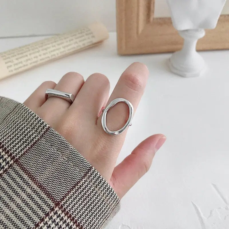 A sterling silver adjustable open ring for women featuring a sleek silver-toned minimalist oval design worn on a finger.