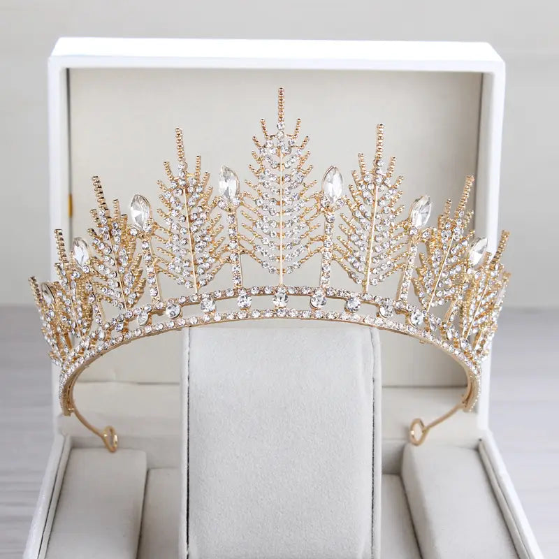 A gold-toned crystal bridal tiara with intricate leaf-like designs and sparkling clear crystals for wedding crown headpiece use.