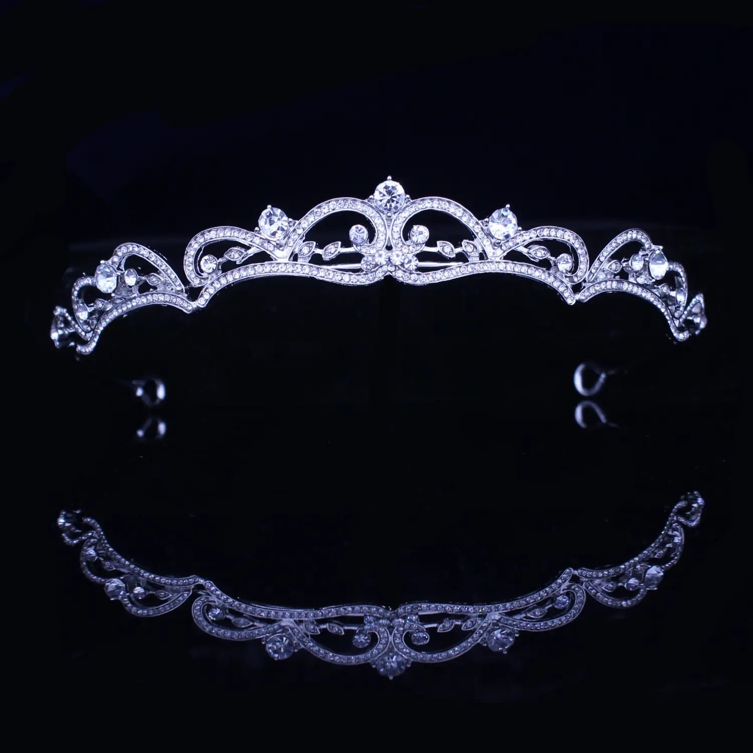 Una diadema de boda floral con tiara de novia de cristal plateado brillante, adornada con trabajo de filigrana intrincado y numerosos cristales transparentes.