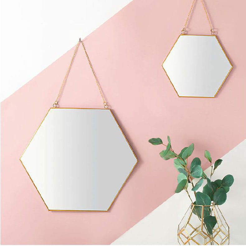 Gold hexagonal wall hanging mirror with gold frame and chain hanging straps.