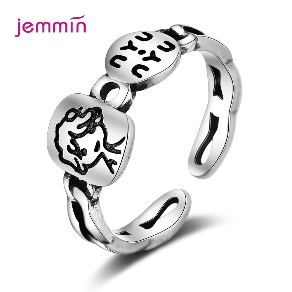 Bague réglable à motif facial en argent sterling Jemmin dans un ton argent, présentant deux breloques arrondies gravées avec un visage stylisé et l’inscription « cyu ».