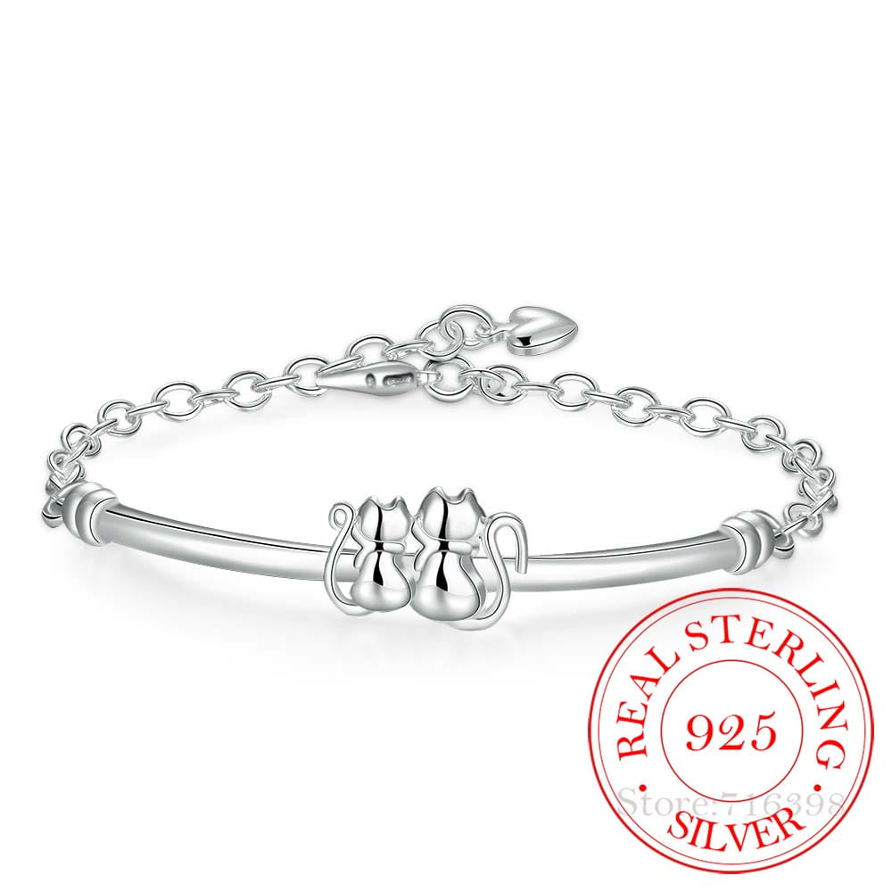 Bracelet en argent sterling avec pendentif couple de chats, présentant un bracelet délicatement poli avec deux charmants sujets de chat réunis et une fermeture de chaîne élégante.
