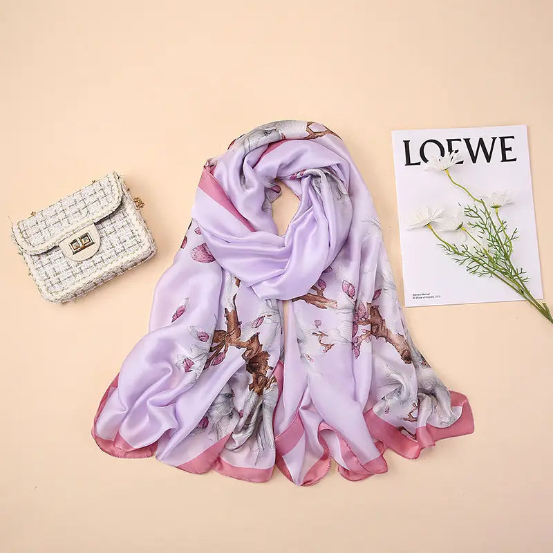 Un châle foulard en soie lilas doux Van Gogh, amandiers en fleurs, avec un motif floral délicat et une bordure en satin rose.