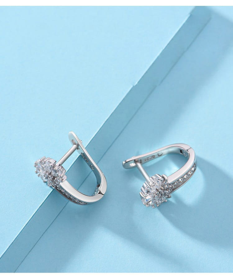 Sterling silver zircon flower hoop earrings featuring silver huggie design adorned with a cluster of sparkling clear crystals and a delicate row of smaller stones along the curve.