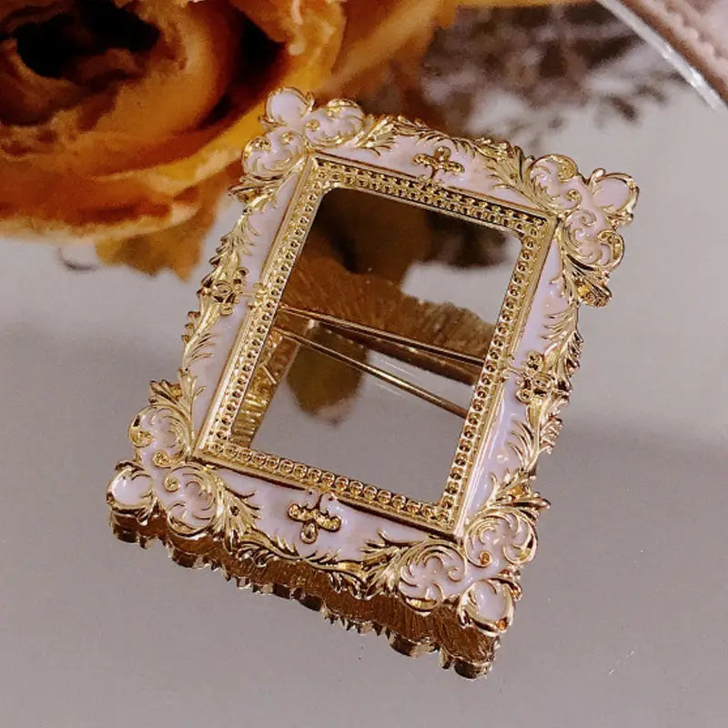 Broche para marco de cuadro con arte de David barroco, con un acabado ornamentado en oro y esmalte rosa pálido, con detalles florales intrincados.