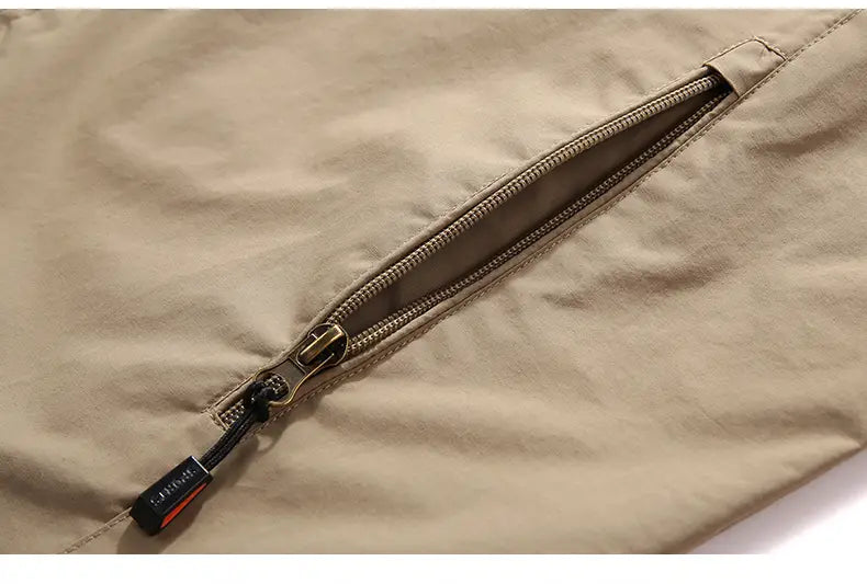 ベージュのメンズ防水ハイキングジャケット。ジッパー開閉式で、黒のプルタブを備えた、屋外用フード付きウィンドブレーカーとして設計された生地です。