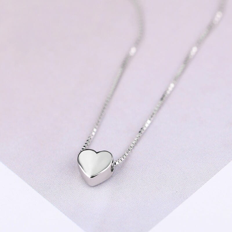 Un collar minimalista con colgante de corazón en plata de ley, con acabado pulido y liso y cadena tipo caja delicada.